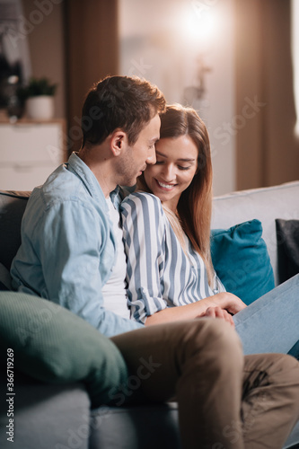 Portrait of a young couple in casual clothes on the couch in hugging each other