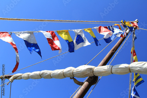 Sea signal flags mounted on the mast against the blue sky, taken close-up. Ship's flags fluttering in the sky. Signals, Morse code. Flagpole.