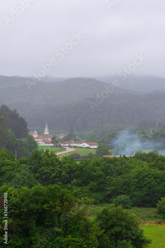 Landscape of a green valley with a small town  a cloudy summer day  in Ruiloba  Cantabria  Europe  vertically