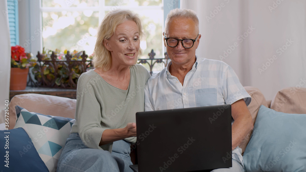 Modern mature couple have fun using laptop at home