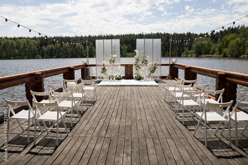 Beautiful wedding ceremony place on the lake with natural materials in white color
