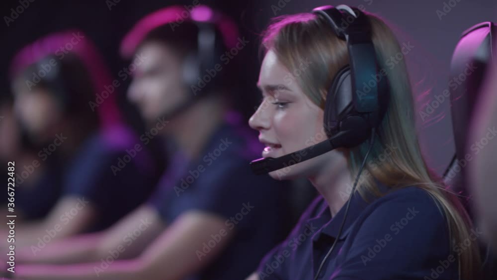 Group of young people taking part in cybersport tournament putting on headphones and starting playing video game Group of young people taking part in cybersport tournament putting on headphones and starting playing video game
