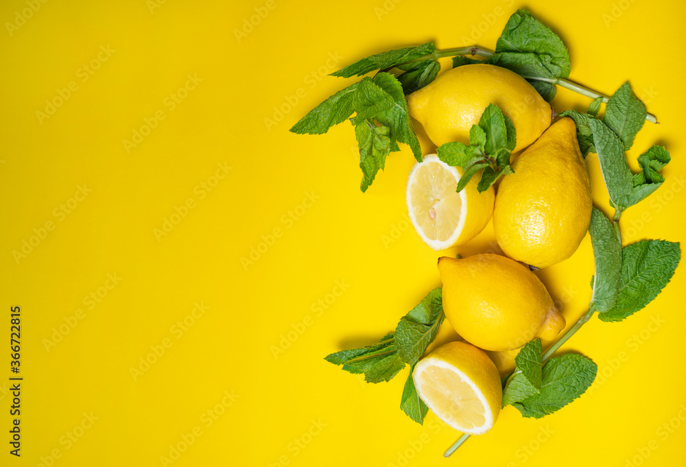 Colourful yellow background with bright fresh and organic lemons and fresh mint, space for text, summer drink preparation