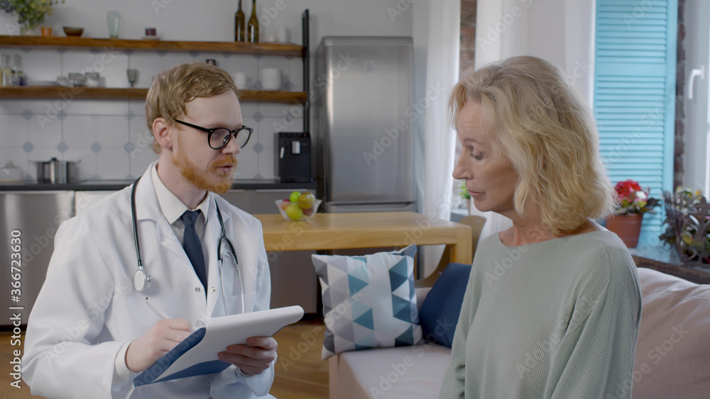 Fototapeta premium Young doctor visiting old mature woman for check-up