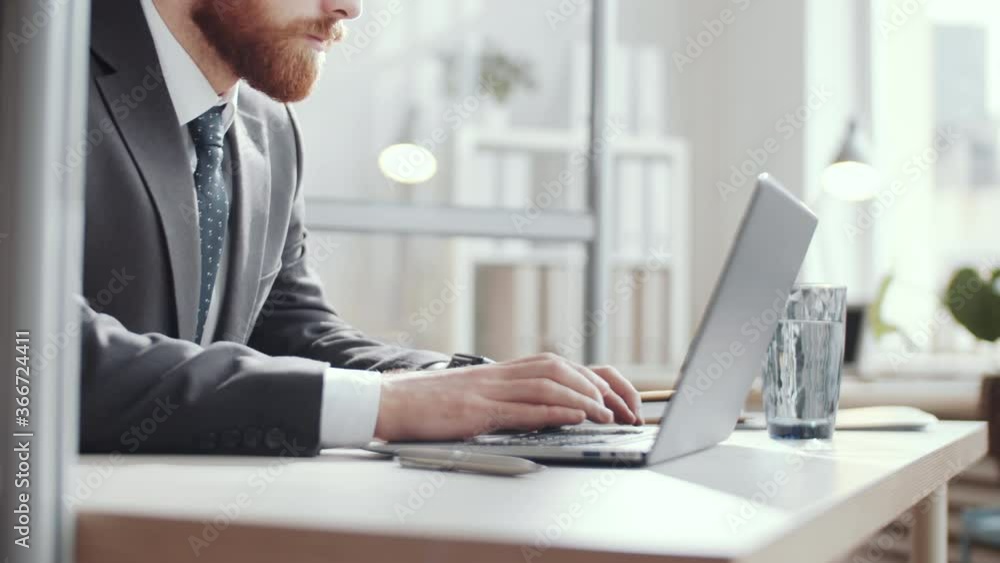 Midsection shot of young caucasian businessman in formalwear working on laptop at desk in the office Midsection shot of young caucasian businessman in formalwear working on laptop at desk in the office