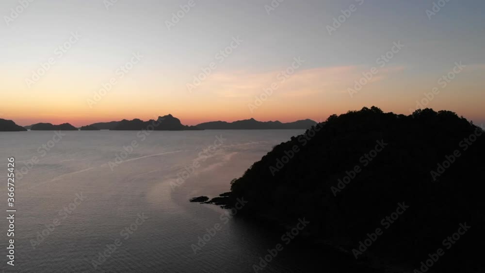 Silhouette Of Coastal Mountains By The Calm Sea Coast During Sunset In El Nido, Palawan, Philippines. - aerial drone Silhouette Of Coastal Mountains By The Calm Sea Coast During Sunset In El Nido, Palawan, Philippines. - aerial drone