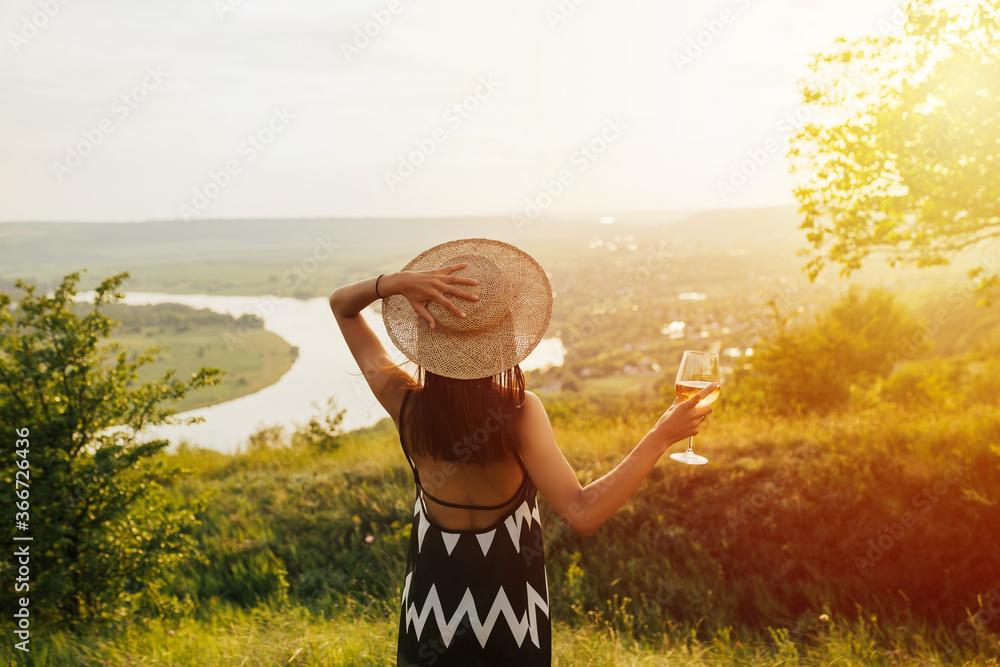 Beautiful woman is straw hat and elegant dress is relaxing, drinking, traveling and enjoying life in vacation. Photo from back. Summer sunny beautiful landscape on background. Relax in nature. Beautiful woman is straw hat and elegant dress is relaxing, drinking, traveling and enjoying life in vacation. Photo from back. Summer sunny beautiful landscape on background. Relax in nature.