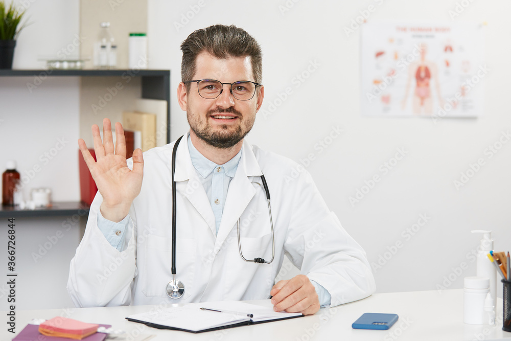 handsome senior doctor showing hi gesture while working online handsome senior doctor showing hi gesture while working online