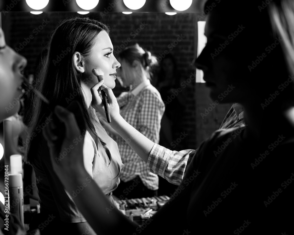 Plus size model get prepared to runway fashion show by make up artist. Black and white backstage concept Plus size model get prepared to runway fashion show by make up artist. Black and white backstage concept