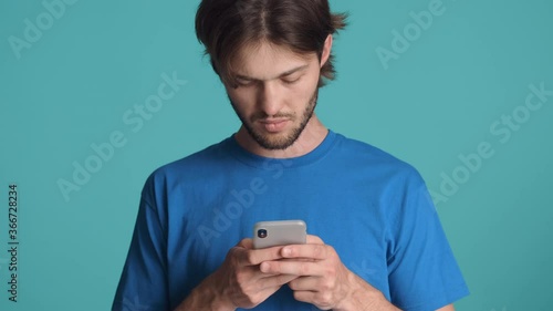 Attractive serious bearded waving no gesture while guy using smartphone over colorful background