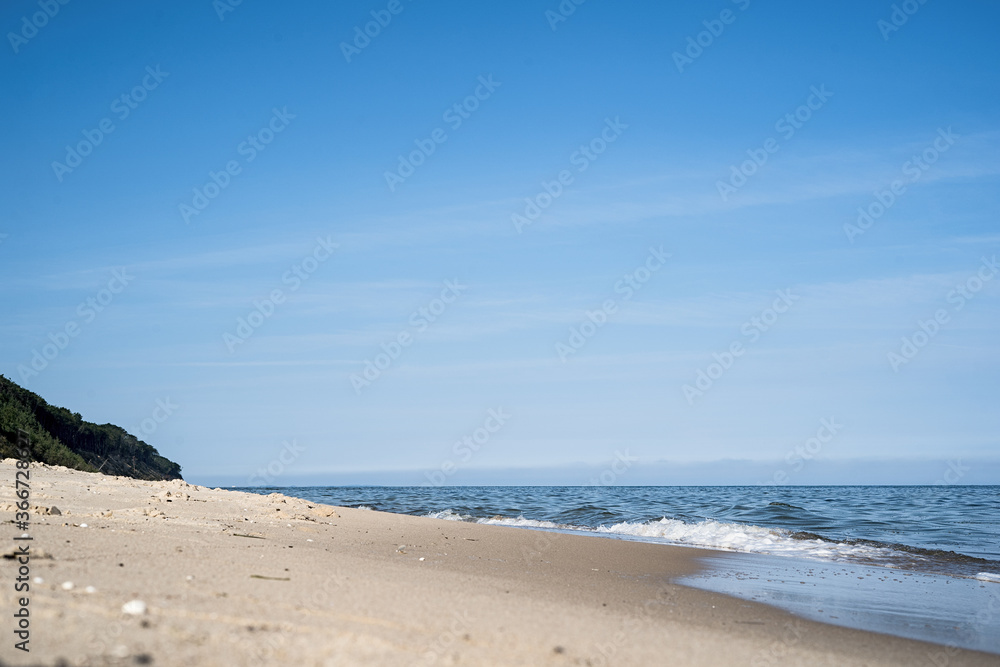 Sandy beach on the Baltic Sea, view of the sea, sandy beach and dunes covered with natural forest