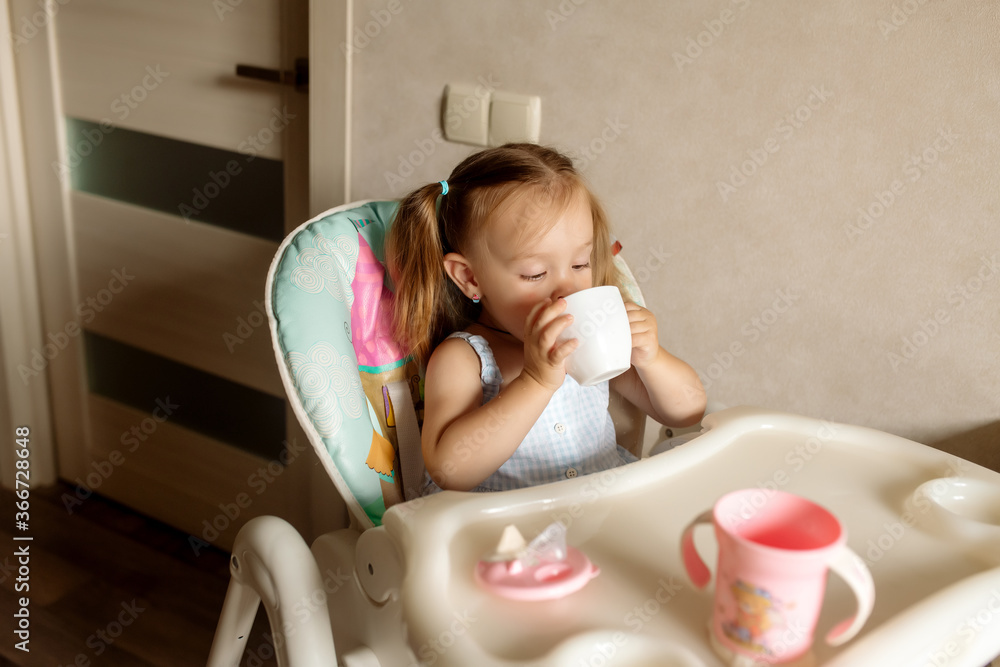 Little girl 2 years old with ponytail hairstyle plays with water, laughs and smiles, sitting in a highchair in the kitchen at home
Little girl 2 years old with ponytail hairstyle plays with water, laughs and smiles, sitting in a highchair in the kitchen at home