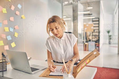 Beautiful young woman working with documents in office