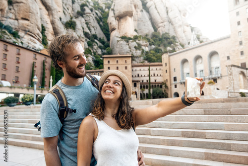 Tourist couple on vacation taking a selfie photo in the montserrat monastery, Barcelona, Spain