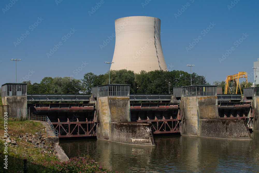 Obraz premium Three locks of a hydropower plant with a machine house. And a cooling tower of a nuclear power plant in the background.
