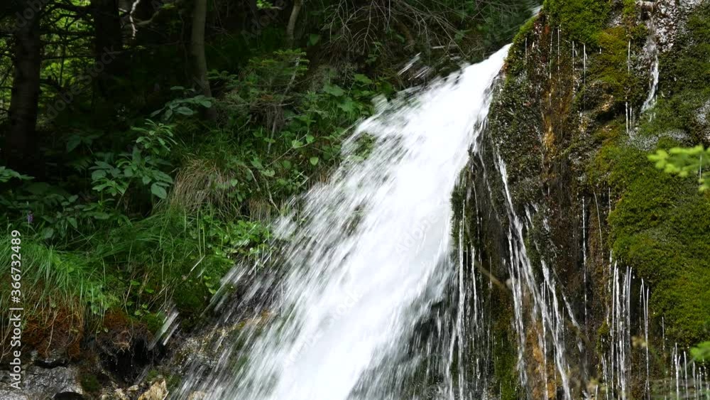 Mountain stream or waterfall flowing between rocks and stones. Foamy Valley Waterfall in Bucegi mountains accessible from Busteni town. Mountain stream or waterfall flowing between rocks and stones. Foamy Valley Waterfall in Bucegi mountains accessible from Busteni town.