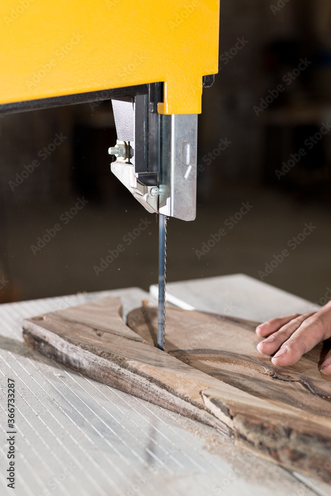 Carpenter hands working on band saw with wooden shape to create interior products. Carpenter hands working on band saw with wooden shape to create interior products.