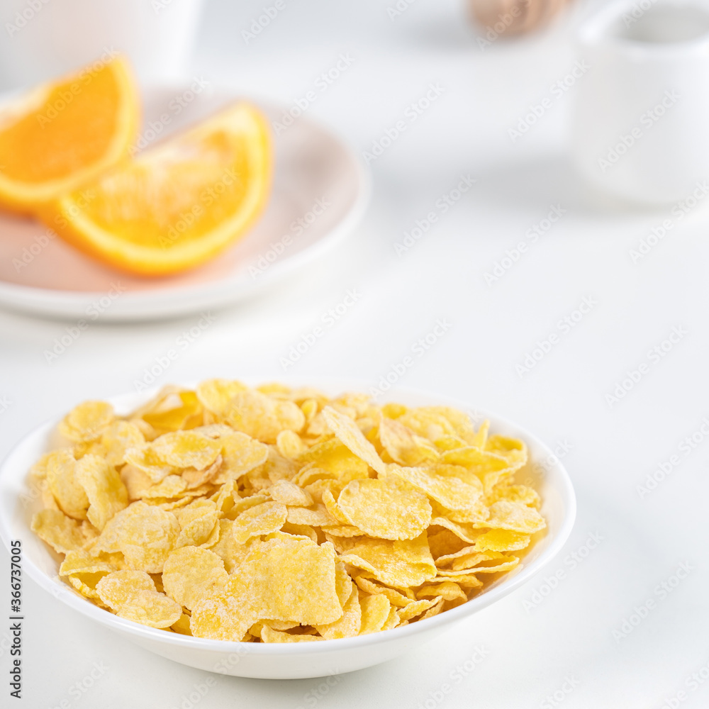 Corn flakes bowl sweeties with milk and orange on white background, close up, fresh and healthy breakfast design concept. Corn flakes bowl sweeties with milk and orange on white background, close up, fresh and healthy breakfast design concept.