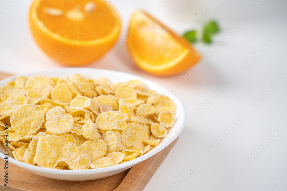 Corn flakes bowl sweeties with milk and orange on white background, close up, fresh and healthy breakfast design concept. Corn flakes bowl sweeties with milk and orange on white background, close up, fresh and healthy breakfast design concept.