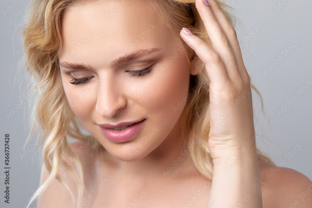 Beautiful smiling blonde woman with curly hair, clean skin and fresh make-up. She has beautiful blue eyes. Aesthetic cosmetology, hair treatment and makeup concept. Beautiful smiling blonde woman with curly hair, clean skin and fresh make-up. She has beautiful blue eyes. Aesthetic cosmetology, hair treatment and makeup concept.