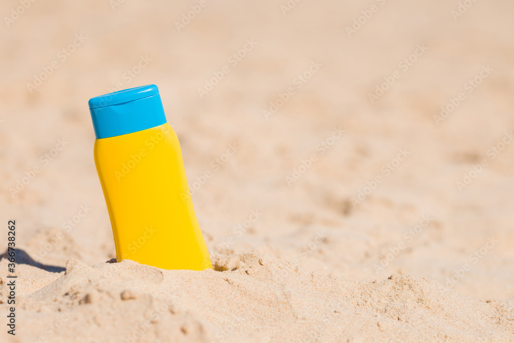 Yellow tube of sunscreen on sand. Safety sunbathing in hot day at beach. Care about skin protection in hot summer. Empty place for text or logo. Closeup. Front view. Yellow tube of sunscreen on sand. Safety sunbathing in hot day at beach. Care about skin protection in hot summer. Empty place for text or logo. Closeup. Front view.