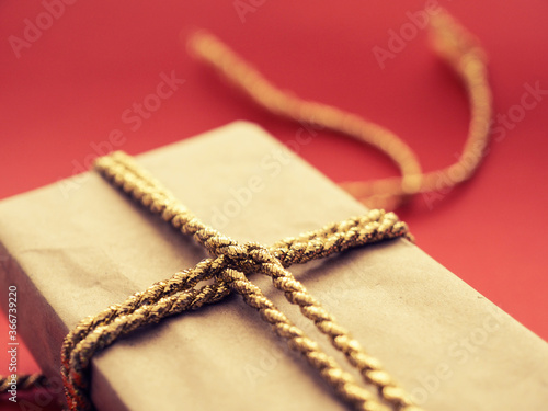 A Christmas present with golden gift bank on a red background