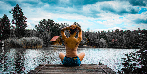 Stampa su tela Girl sitting on a lake dock