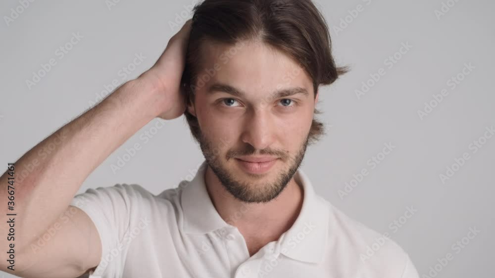 Portrait of handsome bearded guy straightens his hair confidently posing on camera over white background Portrait of handsome bearded guy straightens his hair confidently posing on camera over white background