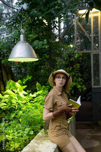 Papier peint Woman botanist dressed in safari style in greenhouse