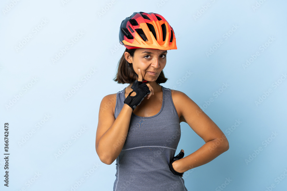 Young cyclist woman isolated on blue background and thinking Young cyclist woman isolated on blue background and thinking