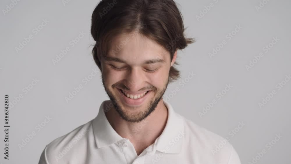 Close up handsome cheerful guy happily looking in camera and nod over gray background Close up handsome cheerful guy happily looking in camera and nod over gray background