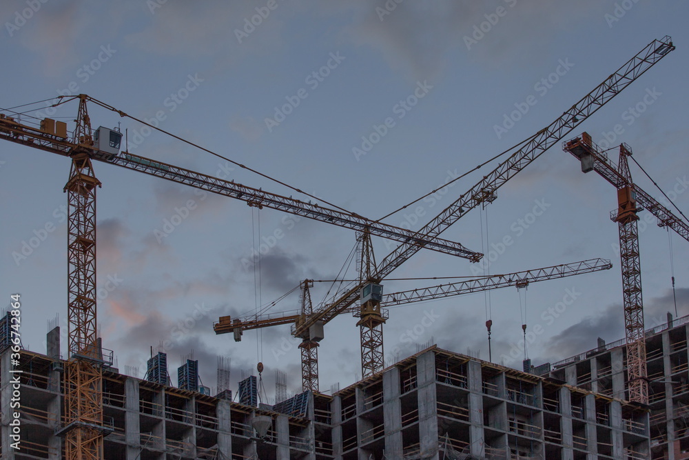 Construction site with cranes against the background of the evening sky Construction site with cranes against the background of the evening sky