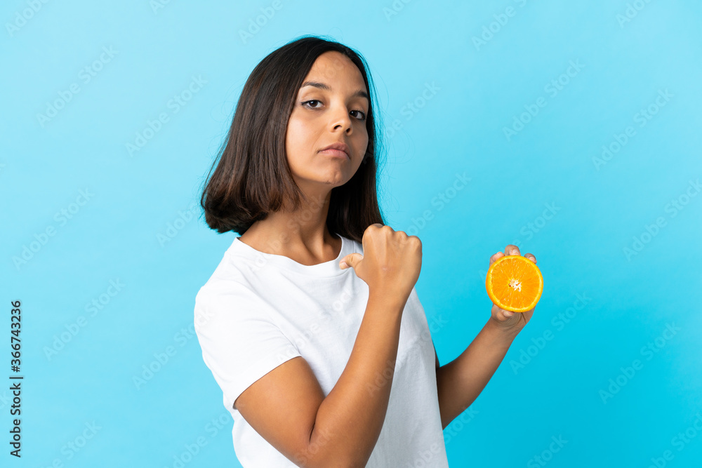 Young asian girl holding an orange isolated on blue background proud and self-satisfied Young asian girl holding an orange isolated on blue background proud and self-satisfied