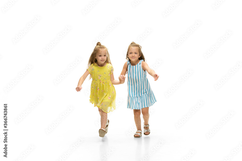 Happy children, little and emotional caucasian girls jumping and running isolated on white background. Looks happy, cheerful, sincere. Copyspace for ad. Childhood, education, happiness concept. Happy children, little and emotional caucasian girls jumping and running isolated on white background. Looks happy, cheerful, sincere. Copyspace for ad. Childhood, education, happiness concept.