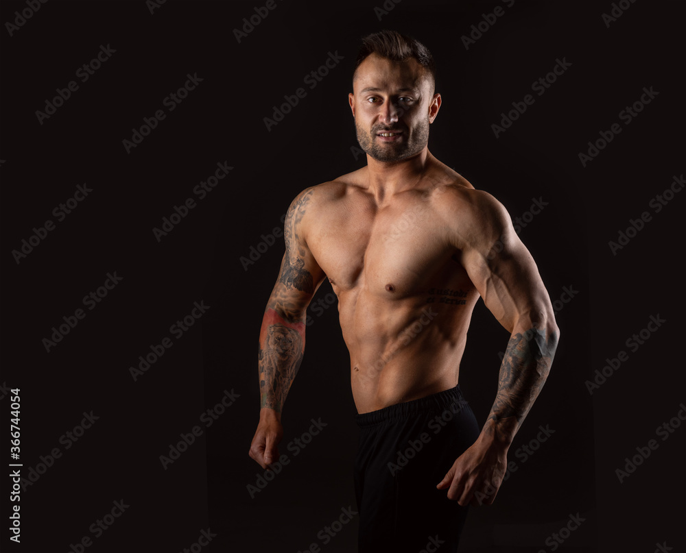 Smiling strong man. Bodybuilder on black background.