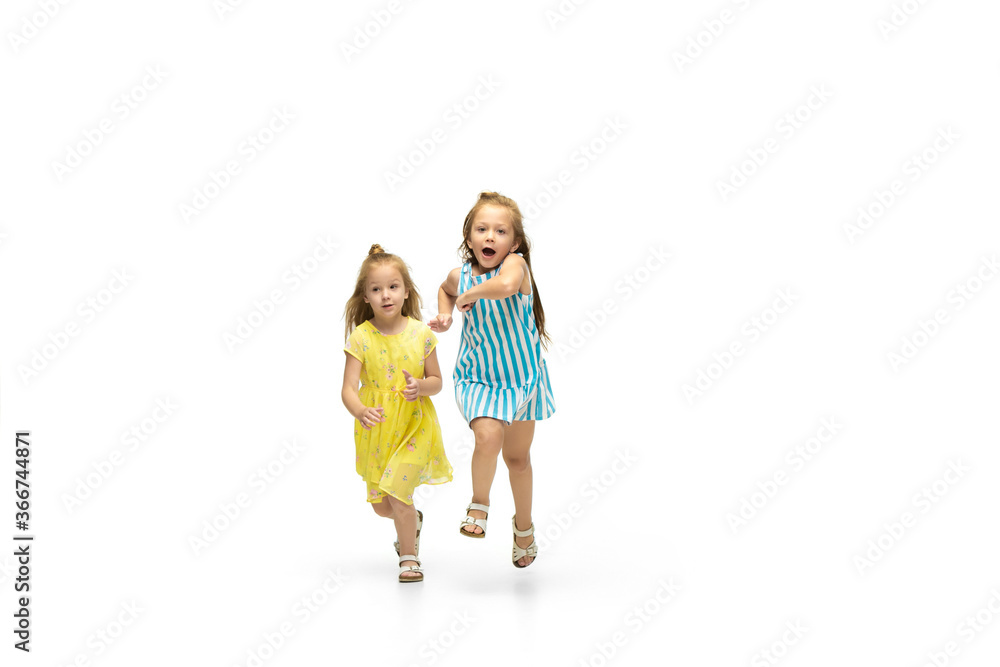 Happy children, little and emotional caucasian girls jumping and running isolated on white background. Looks happy, cheerful, sincere. Copyspace for ad. Childhood, education, happiness concept. Happy children, little and emotional caucasian girls jumping and running isolated on white background. Looks happy, cheerful, sincere. Copyspace for ad. Childhood, education, happiness concept.