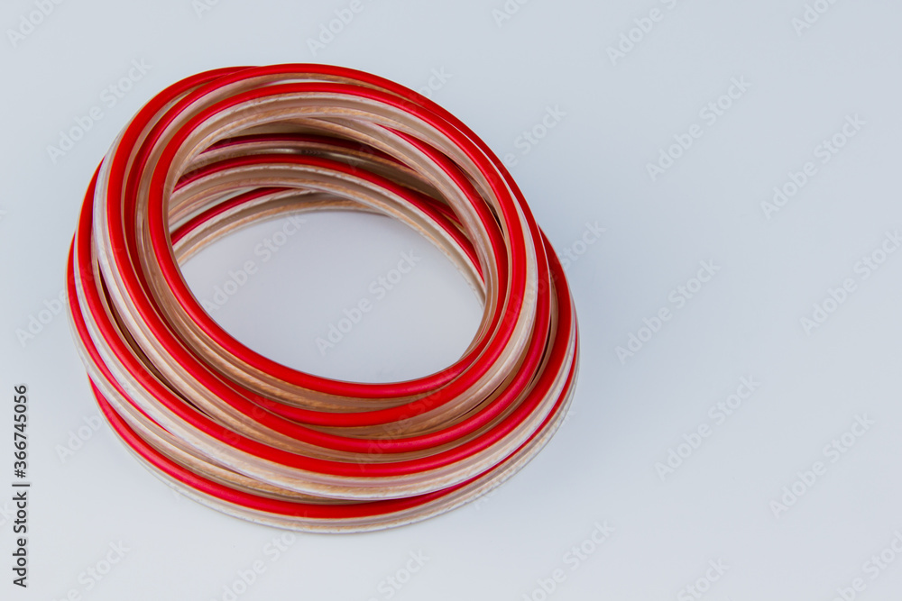 Red and white electric wire wrapped in a roll on a white background, close up. Red and white electric wire wrapped in a roll on a white background, close up.
