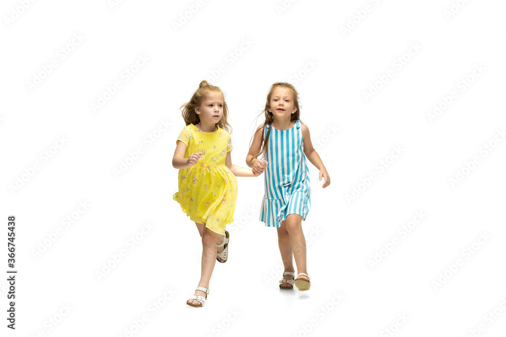 Happy children, little and emotional caucasian girls jumping and running isolated on white background. Looks happy, cheerful, sincere. Copyspace for ad. Childhood, education, happiness concept. Happy children, little and emotional caucasian girls jumping and running isolated on white background. Looks happy, cheerful, sincere. Copyspace for ad. Childhood, education, happiness concept.