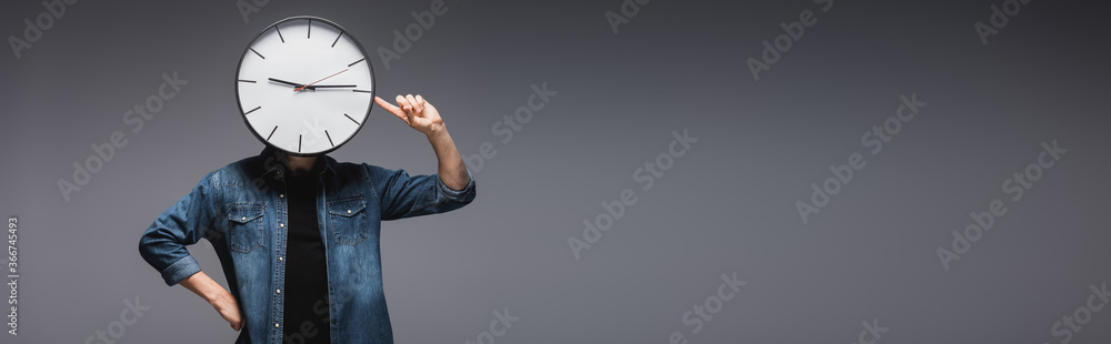 Panoramic orientation of man pointing with finger at clock on head on grey background, concept of time management - obrazy, fototapety, plakaty 