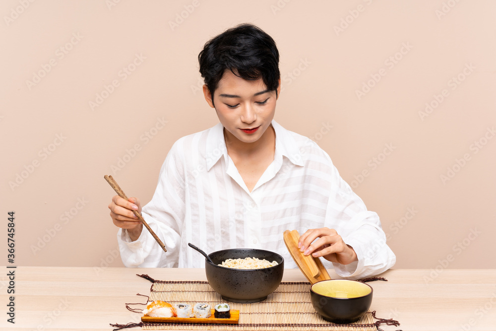 Young Asian girl in a table with bowl of noodles and sushi Young Asian girl in a table with bowl of noodles and sushi