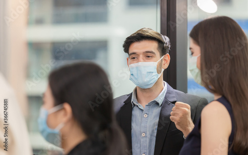 Success and Teamwork concept, Group of young business people wear protection face mask against coronavirus chatting after the meeting