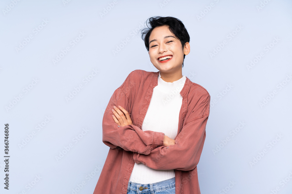 Young Asian girl over isolated blue background keeping the arms crossed in frontal position Young Asian girl over isolated blue background keeping the arms crossed in frontal position
