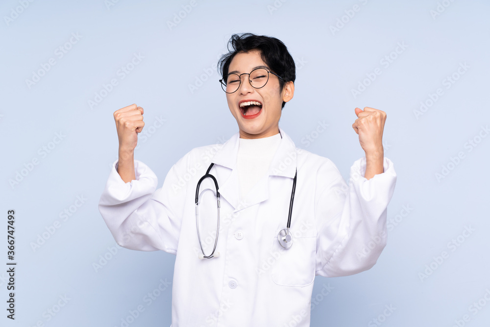 Doctor Asian woman over isolated blue background celebrating a victory Doctor Asian woman over isolated blue background celebrating a victory