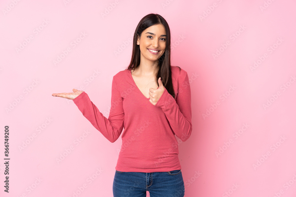 Young caucasian woman over isolated background holding copyspace imaginary on the palm to insert an ad and with thumbs up Young caucasian woman over isolated background holding copyspace imaginary on the palm to insert an ad and with thumbs up