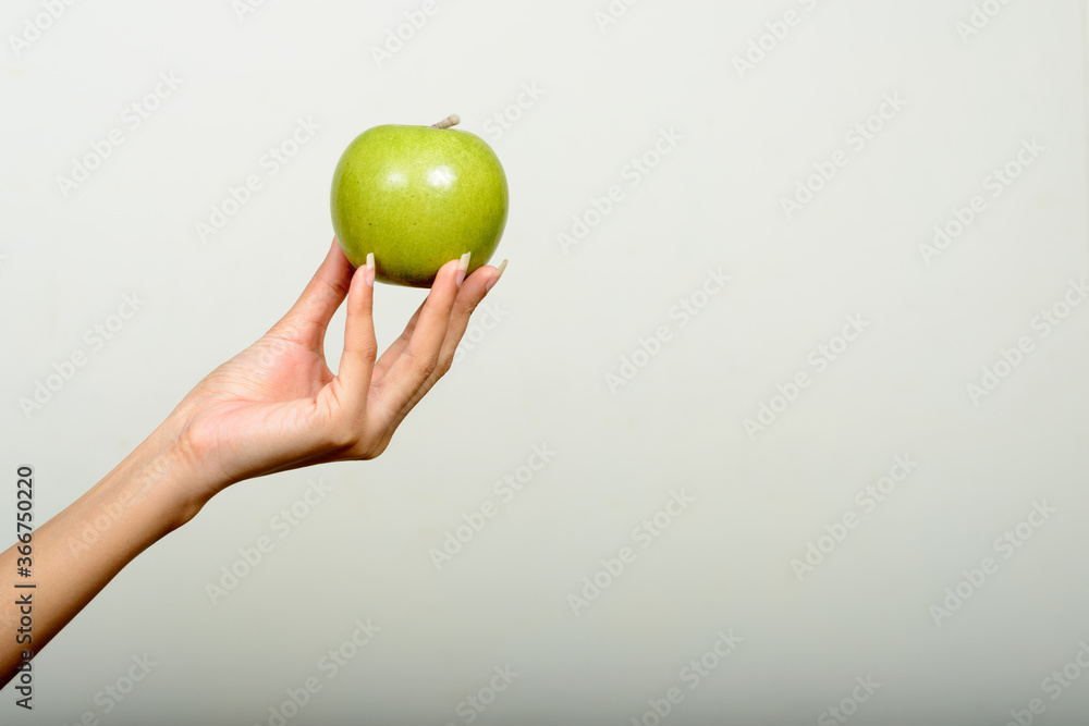 Hand of young Asian woman holding green apple Hand of young Asian woman holding green apple