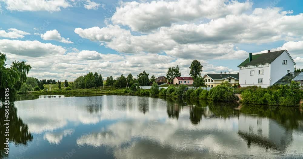 Village landscape with a small lake, time lapse of clouds reflected in the water, beautiful summer landscape Village landscape with a small lake, time lapse of clouds reflected in the water, beautiful summer landscape
