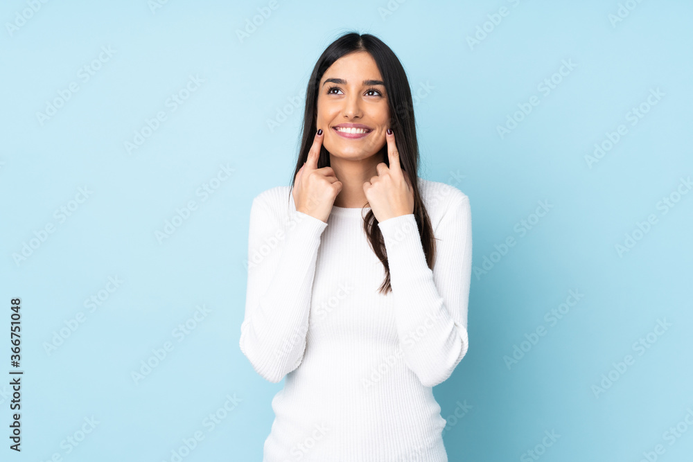 Young caucasian woman isolated on blue background smiling with a happy and pleasant expression Young caucasian woman isolated on blue background smiling with a happy and pleasant expression