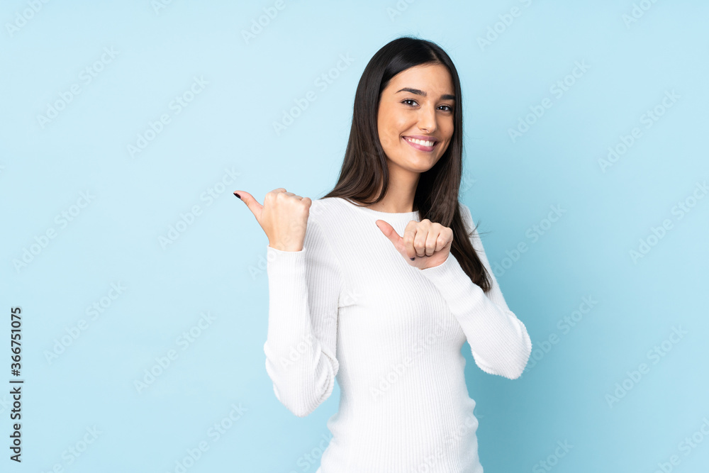 Young caucasian woman isolated on blue background pointing to the side to present a product Young caucasian woman isolated on blue background pointing to the side to present a product