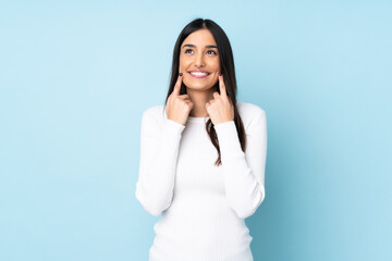 Young caucasian woman isolated on blue background smiling with a happy and pleasant expression