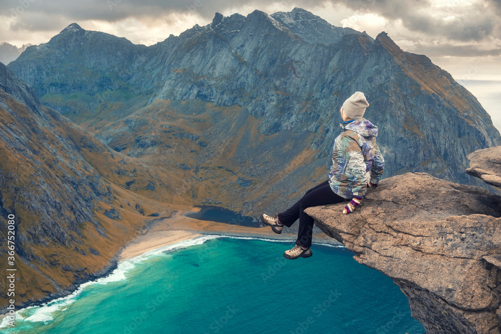 Brave woman over turquoise sea water among the Mountains on the beach of Kvalvika view from Mount Ryten